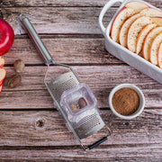 Microplane | Professional Series Fine Grater with nutmeg crusher, grating nutmeg beside sliced apples, highlighting its precision and versatility in enhancing dishes.