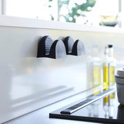 Yamazaki Home's Magnetic Pot Holders in black, mounted on a kitchen wall, offer a sleek, modern solution for effortlessly handling hot cookware.