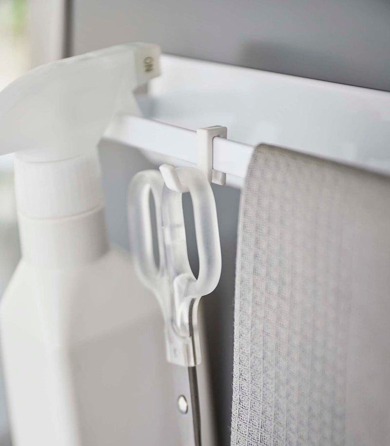 Yamazaki Home | Magnetic Kitchen Towel Hanger, Steel, White, holding a spray bottle, scissors, and cloth on a white rail, showcasing versatile kitchen organization.