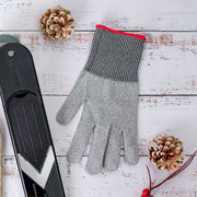 Cut-resistant gray knit glove with red cuff beside black mandoline slicer, designed for kitchen safety by Microplane, displayed on whitewashed wood with decorative pine cones and berries.