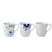 Royal Copenhagen | Gifts With History Cups, Set of 3: Three fluted porcelain mugs featuring intricate blue floral designs and plain white, showcasing timeless elegance and craftsmanship.