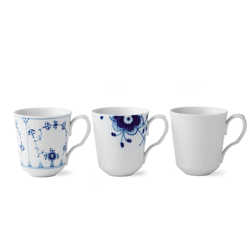 Royal Copenhagen | Gifts With History Cups, Set of 3: Three fluted porcelain mugs featuring intricate blue floral designs and plain white, showcasing timeless elegance and craftsmanship.