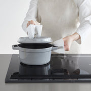 Person lifts pot lid using Yamazaki Home | Magnetic Pot Holders, Silicone, Black, enhancing kitchen safety on induction cooktop.