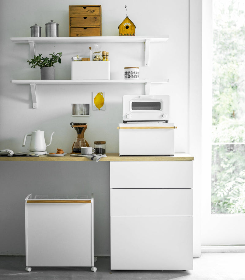 Yamazaki Home Simple Steel Bread Box in white and wood, doubles as storage, under a toaster oven in a minimalist kitchen corner with coffee setup.
