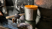 Lodestone Candles | Sea Buckthorn Candle on a table with shells, embodying coastal serenity with oceanic and floral notes, part of The Botanist Collection.