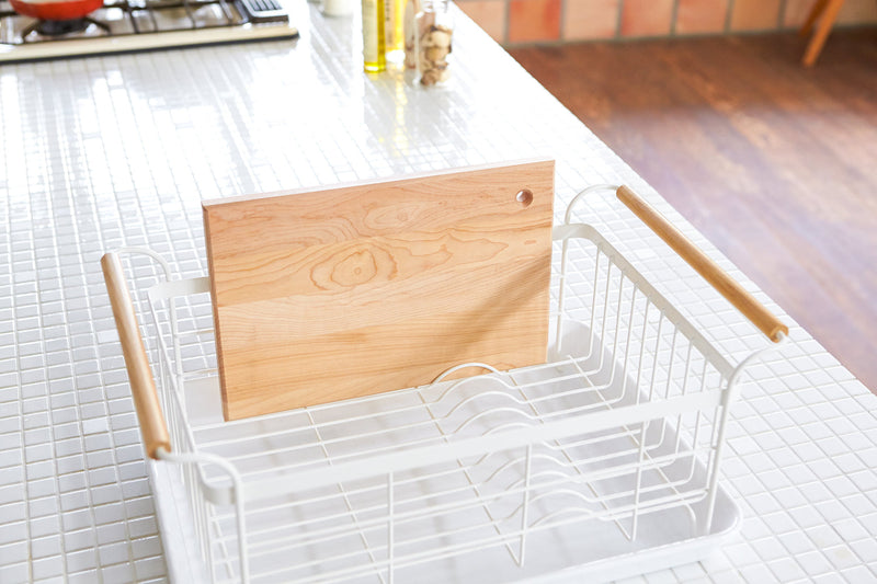 Yamazaki Home | Steel + Wood Dish Rack with Drainer Spout, featuring a sleek steel frame, wooden handles, and a cutting board in a modern kitchen setting.