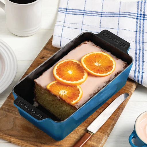 Le Creuset Signature Loaf Pan, 9-inch, Marseille with an orange-glazed cake, highlighting its ergonomic handles and premium enameled cast iron construction.