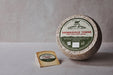 Sweet Grass Dairy | Thomasville Tomme cheese wheel with a slice cut, showcasing its natural rind and semi-soft texture.