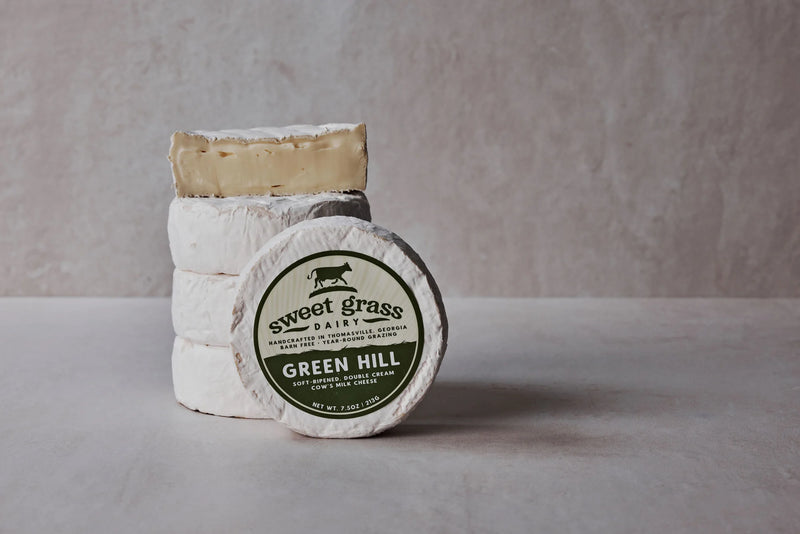 Sweet Grass Dairy | Green Hill Cheese: A stack of round, soft-ripened white cheese wheels with a bloomy rind, reflecting artisanal Southern cheesemaking.