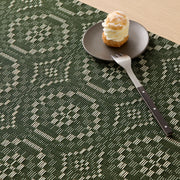 Chilewich | Overshot Rectangular Placemat, Thyme, showcases interlocking circles under a cream-puff pastry on a side plate, complemented by a fork/knife with a wooden handle.