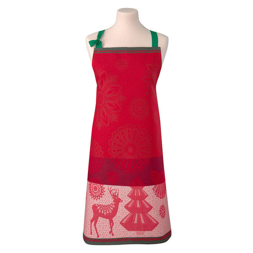 Le Jacquard Français | Lumiere D'Etoiles Apron on a dress form, featuring red fabric, green straps, holiday motifs of reindeer and fir trees.