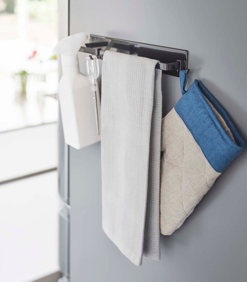 Yamazaki Home Magnetic Kitchen Towel Hanger in use, holding kitchen tools and towel, magnet-mounted for easy access, ideal for organizing your kitchen essentials efficiently.