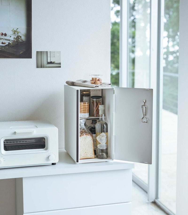 Yamazaki Home | Bread Box, Vertical, Steel, Black holds bread inside a minimalist kitchen cabinet, enhancing decor and reducing clutter while ensuring optimal airflow.