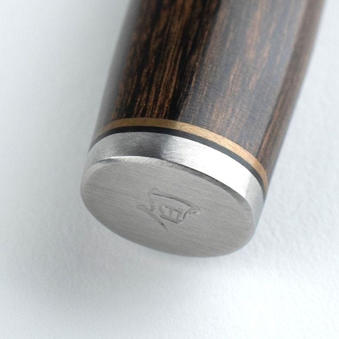 Shun Premier Utility 6.5 Walnut knife's end features a dark wood handle, brass and black rings, and a stainless-steel cap with a logo.