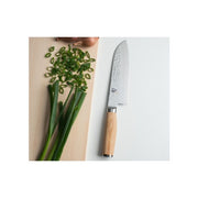 Shun | Premier Blonde Santoku, 7 knife with hammered blade and blonde Pakkawood handle, on a board with scallions and shallots, showcasing its versatility in kitchen tasks.