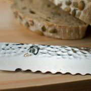 Shun | Premier Blonde Bread Knife, 9, serrated blade on a wooden board, perfectly slices seeded whole-grain bread without crushing, ideal for crusty or tender loaves.