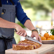 Chef slicing beef with a Shun Premier Chef's Walnut, 8 inches knife, showcasing its hammered finish and ergonomic handle in a culinary setting.