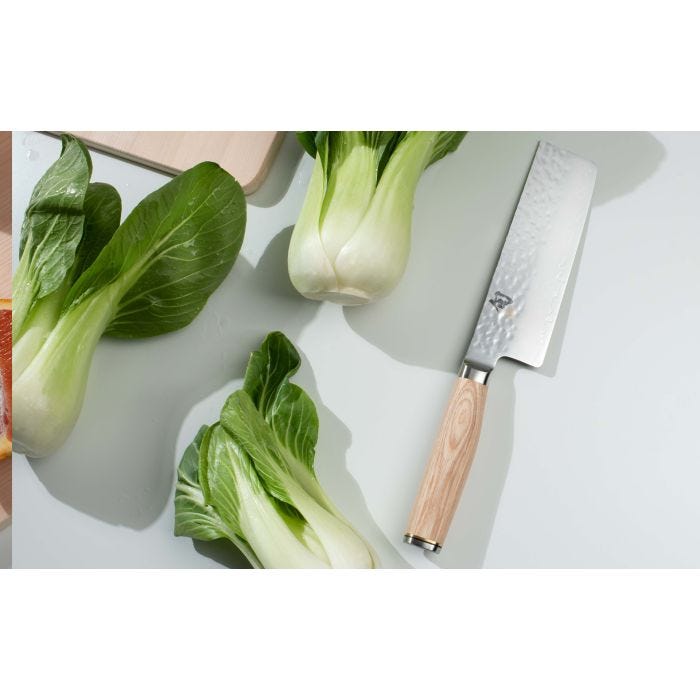 Shun Premier Blonde Nakiri, 5.5 with a hammered finish blade and blonde Pakkawood handle, displayed beside baby bok choy on a light work surface.