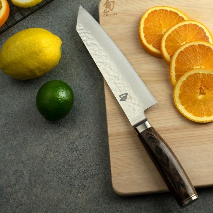 Shun Premier Kiritsuke Walnut, 8, knife on a cutting board with sliced oranges, showcasing its precision and versatility for kitchen tasks.