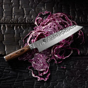 Shun Premier Kiritsuke Walnut, 8, with a hammered finish blade and dark wooden handle, rests on shredded cabbage, showcasing its versatility and precision.