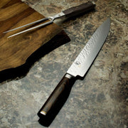 Shun Premier Carving Set Walnut, 2-Piece on marble countertop, featuring a santoku-style knife and carving fork with dark wood handles, perfect for elegant culinary presentations.