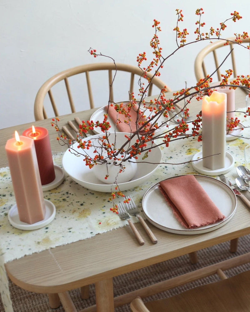 The Floral Society Ceramic Flower Frog Bowl on a table, elegantly holding red berries in a white vase, surrounded by candles and tableware.