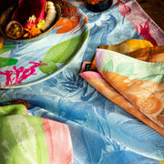 Le Jacquard Français | Équateur Tea Towel, Orange, displayed in a vibrant, tropical-themed setting, enhancing a colorful dining experience with exotic fruit and floral accents.
