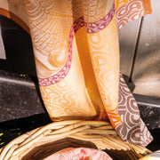 Le Jacquard Francais | Potager D'Hiver Tea Towel, Orange, drapes over a wicker basket, showcasing warm-toned geometric motifs, ideal for enhancing kitchen aesthetics.