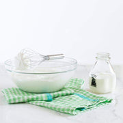 Caravan Home | 20 x 30 Lime & Aqua Towels under a glass bowl with whipped cream, whisk, and vintage cream bottle on a marble countertop.