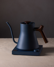 FELLOW | Stagg EKG Pro Electric Kettle, Stone Blue w/ Walnut, featuring a precision spout and wooden accents, ideal for brewing enthusiasts seeking controlled, efficient pour-over coffee preparation.