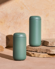 FELLOW | Carter Move Mug, Smoke Green / 16 oz, shown on stones, designed for spill-free, flavor-preserving travel, perfect for coffee lovers on the go.