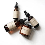 Amber-glass bottles of Among the Flowers | Man Mist, Wood Pile, including body butter, after shave, and a dropper bottle, on a white background.