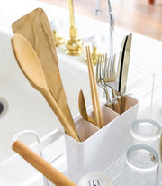 Yamazaki Home | Steel + Wood Dish Rack with Drainer Spout, featuring utensil caddy with wooden tools, bamboo chopsticks, stainless-steel cutlery, and two drying glasses.
