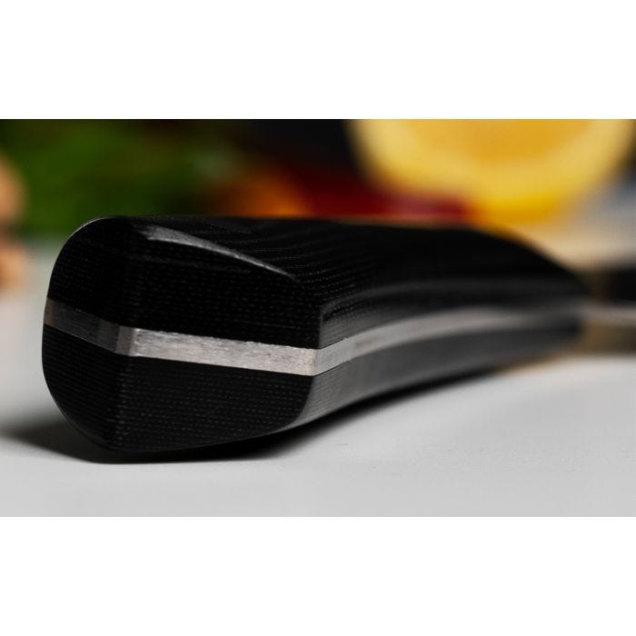 Shun Narukami 8 Chef's Knife handle with full-tang construction, showcasing durable riveted Micarta, resting on a surface with blurred produce in the background.