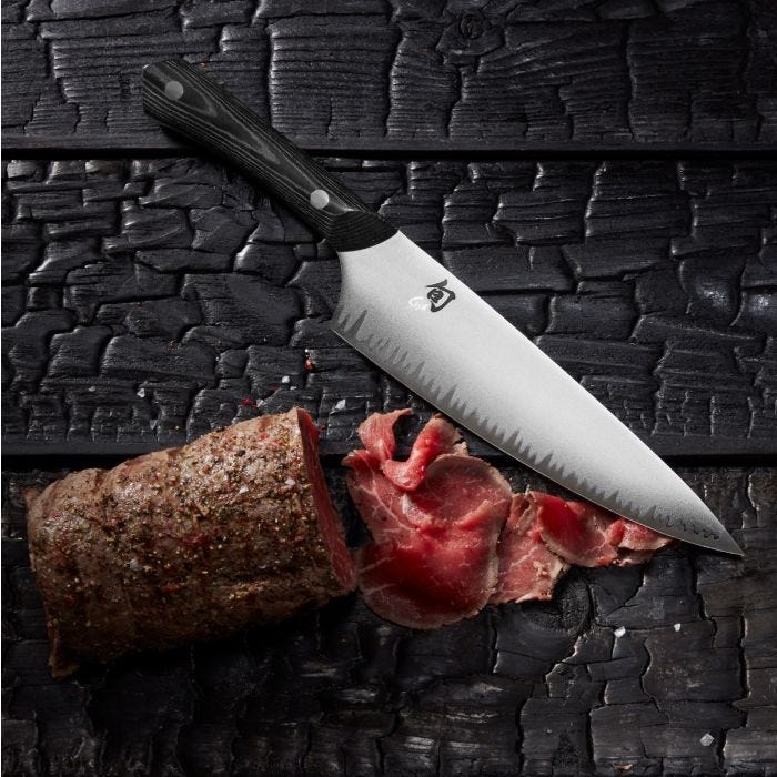 Shun Narukami 8 Chef's Knife with Damascus-style blade on charred-wood cutting surface, next to thinly sliced beef, showcasing its precision and craftsmanship.