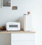 Yamazaki Home Bread Box, Vertical, Steel + Wood sits elegantly on a minimalist kitchen counter, blending seamlessly with Scandinavian-inspired decor and compact appliances.