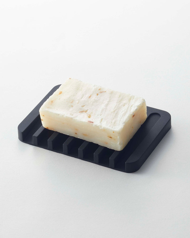 Yamazaki Home | Flow Self-Draining Soap Tray: Handmade soap on a silicone tray with ridged design for efficient drainage, ensuring longevity and easy cleaning.