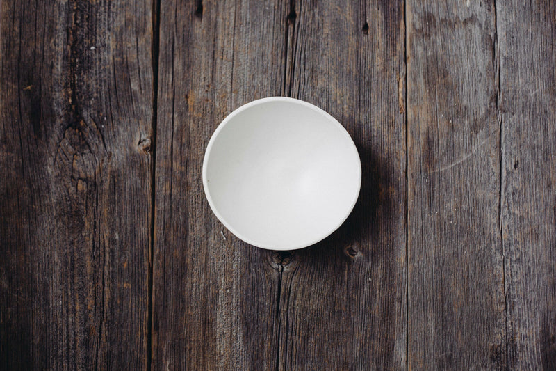 Looks Like White | Scandi Cereal Bowl, a plain white ceramic bowl, viewed from above on a rustic wooden surface, embodying simplicity and natural elegance.