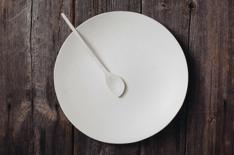 Looks Like White | Scandi Cereal Bowl: A minimalist, hand-painted white bowl by Trudy Crane, showcasing organic lines, on a dark wood surface.
