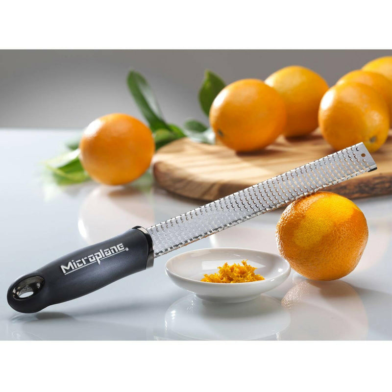 Microplane Premium Zester, Grater - Classic Blue on tabletop with freshly grated orange zest and whole orange, ideal for precise zesting and grating.