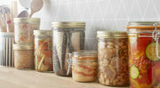 Le Parfait Super Jars (1L) on a countertop, showcasing preserved foods like pickled vegetables and fish, ideal for sustainable storage and canning.