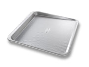 USA Pan | Cookie Tray Pans - Medium features an innovative scoop design with a secure handle for easy cookie release and smooth transfer to cooling racks.