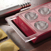 Marcato Ravioli Tablet Pasta Maker showing a close-up of the tool with ravioli, emphasizing its functionality for creating homemade Italian pasta.