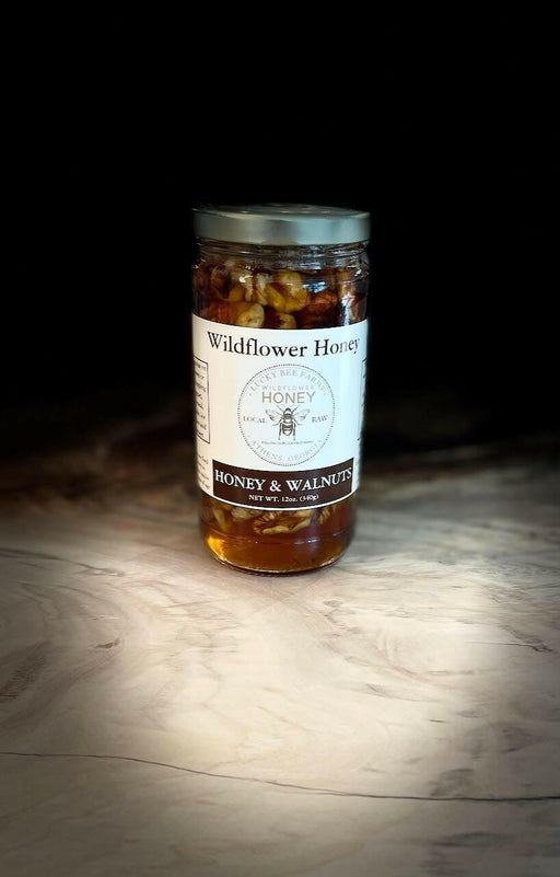 Lucky Bee Farms Honeycomb Jar, showcasing raw, unfiltered honey from Athens, GA, beside a labeled nut jar and a honey bottle on a table.
