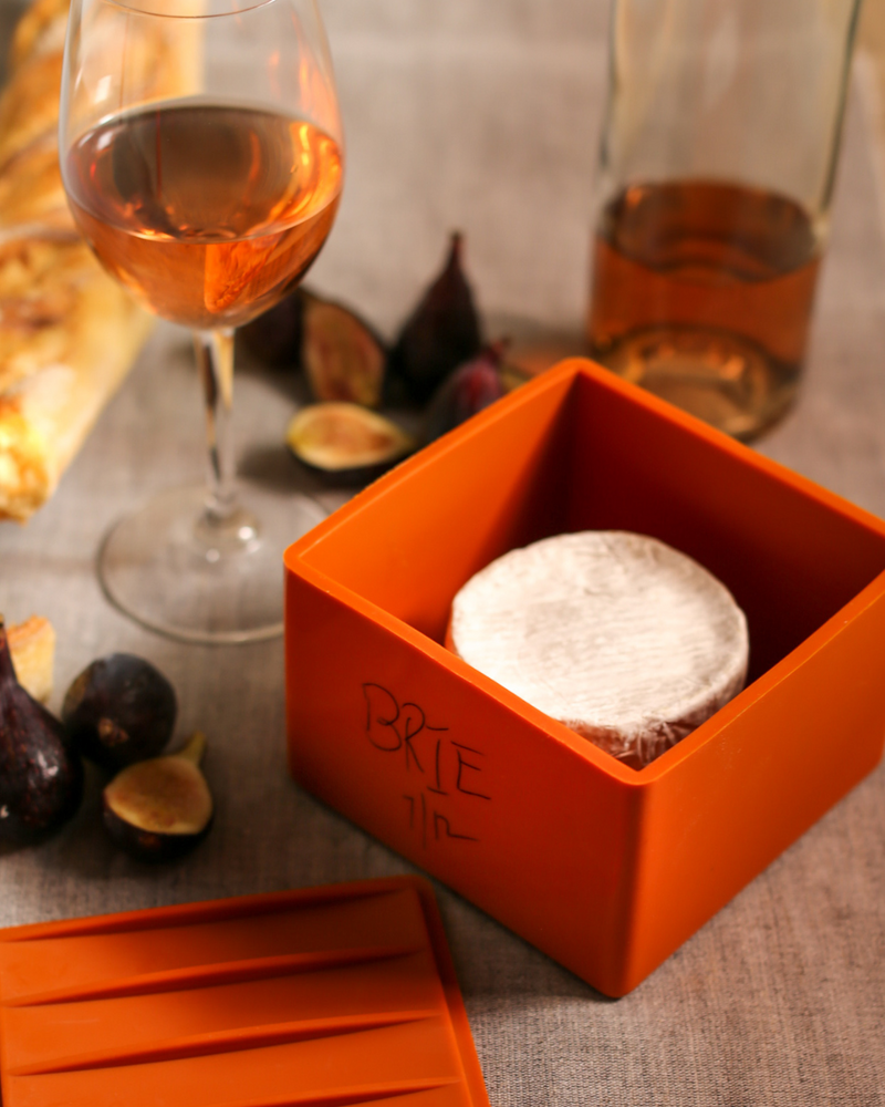 CapaBunga | Cheese Vaults - Soft Cheese - Biscuit (yellow) beside a glass of wine, highlighting its innovative design for preserving cheese freshness and flavor.