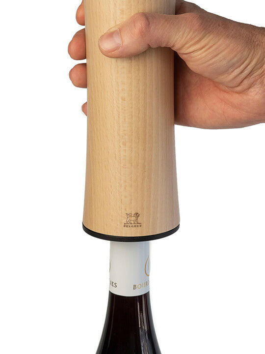 Hand holding Peugeot | Elis Reverse Rechargeable Electric Corkscrew - Natural over wine bottle, highlighting its wooden body and Peugeot logo, showcasing its elegant design and functionality.