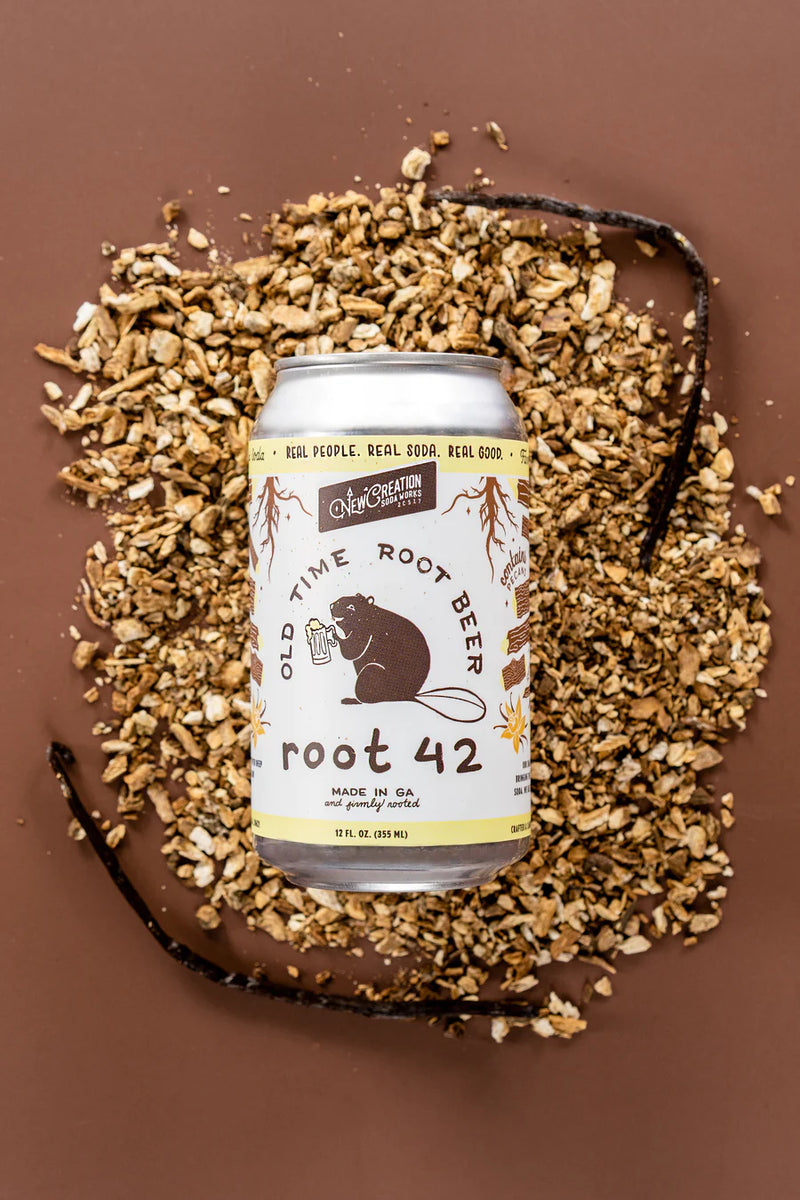 New Creation Soda Works' Krümkake Butter Pecan Cream Soda can on wood chips, highlighting its silky, creamy texture and unique pecan and vanilla blend.