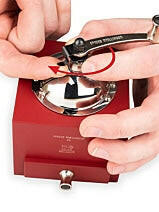 Hands using snap-ring pliers on a Peugeot | Roellinger Pepper Mill, 5 inches - Red, highlighting its intricate design and functional craftsmanship.