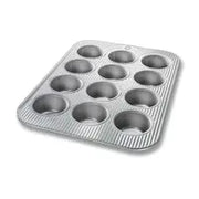 Mini muffin pan with 24 cavities by USA Pan, featuring Americoat nonstick coating and corrugated design for even baking, perfect for bite-sized treats.