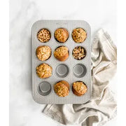 Mini muffin pan with 24 cavities, crafted from heavy-gauge aluminized steel, featuring nonstick coating and corrugated design for even baking, by USA Pan.